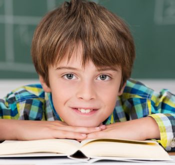 Young boy in school surrounded by textbooks